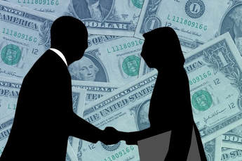 Two career professionals are silhouetted shaking hands, a man and a woman.  
